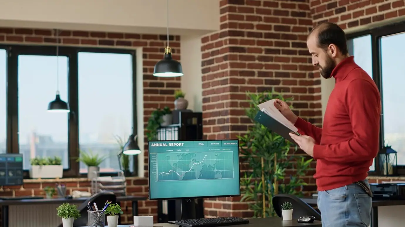 Junger Geschäftsmann nutzt auf dem Bildschirm angezeigte Gewinndaten des Handelsmarkts, um eine finanzielle Investition zu tätigen, und betrachtet Aktienchart-Statistiken. Männlicher Broker analysiert den Hedgefonds-Trend und den Devisenhandel.