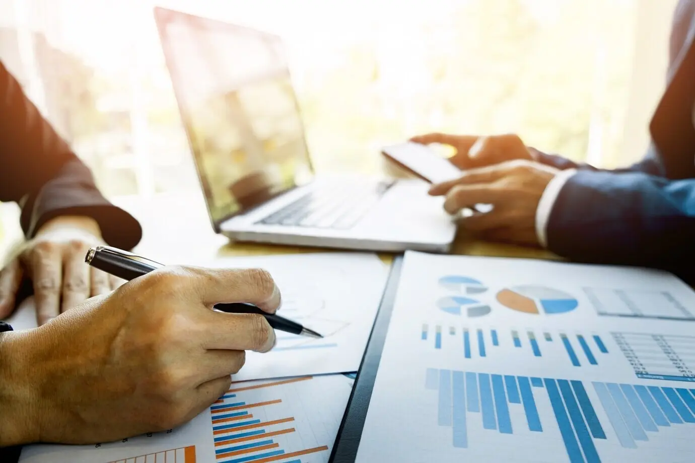 Teamarbeitsprozess. Ein Team junger Business-Manager arbeitet an einem neuen Startup-Projekt. Laptop auf einem Holztisch, Tippen auf der Tastatur, Nachrichten schreiben, Diagrammpläne analysieren.